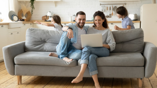 Happy parents using laptop while kids playing funny game