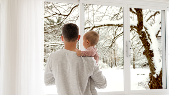 Parent holding child looking outside at the snow